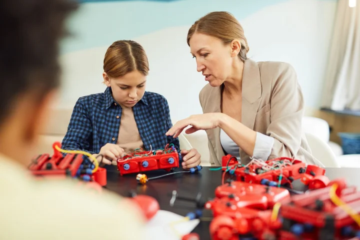 Eine Lehrkraft unterstützt einen Schüler bei einem Robotik-Projekt