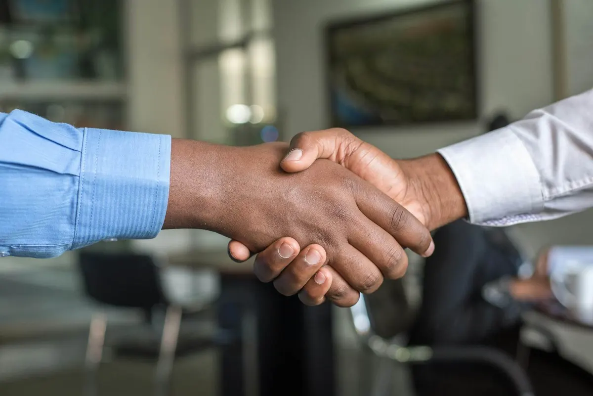 Zwei Personen geben sich zur Begrüßung die Hand